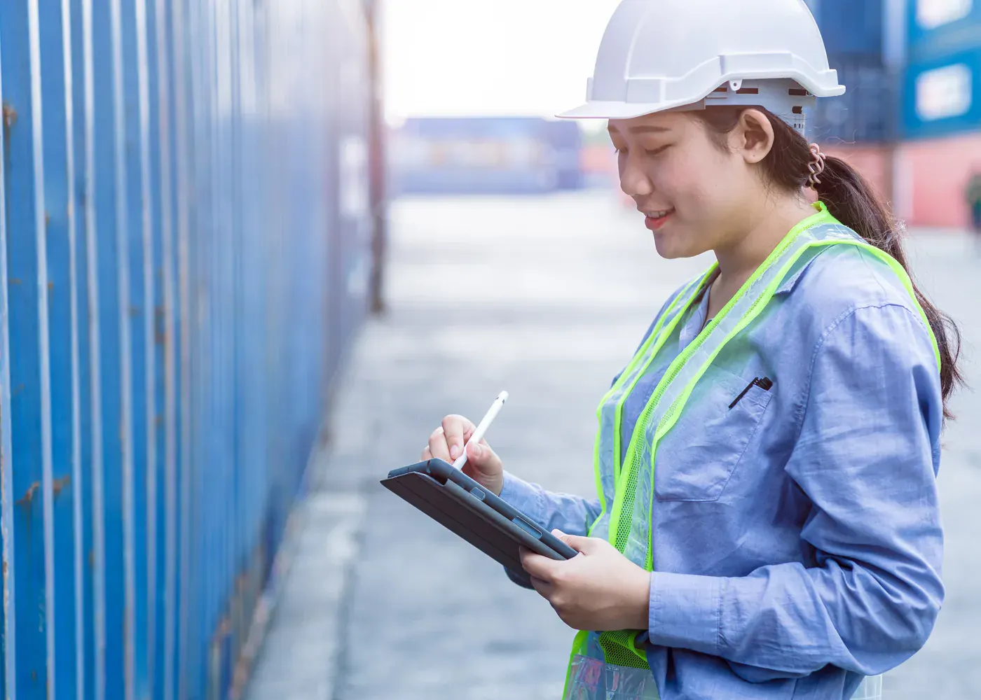 Customs and logistics specialist checking cargo information beside shipping containers